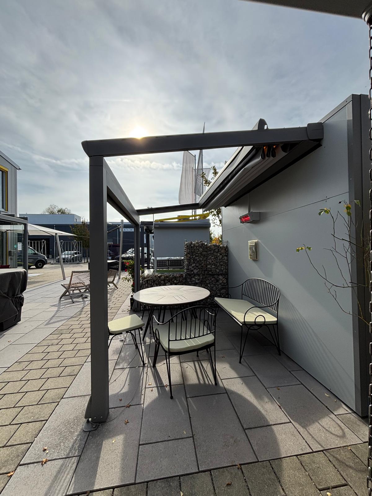 Terrassenüberdachung mit ausfahrbarem Sonnenschutz und Infrarot-Heizstrahler im Außenbereichેહ